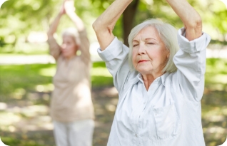 Stock image of two serene old women doing Qigong exercise in the park.
