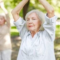 Stock image: Serene elderly woman practicing Qi Gong exercises in the park, symbolising participation in the AIBL study.